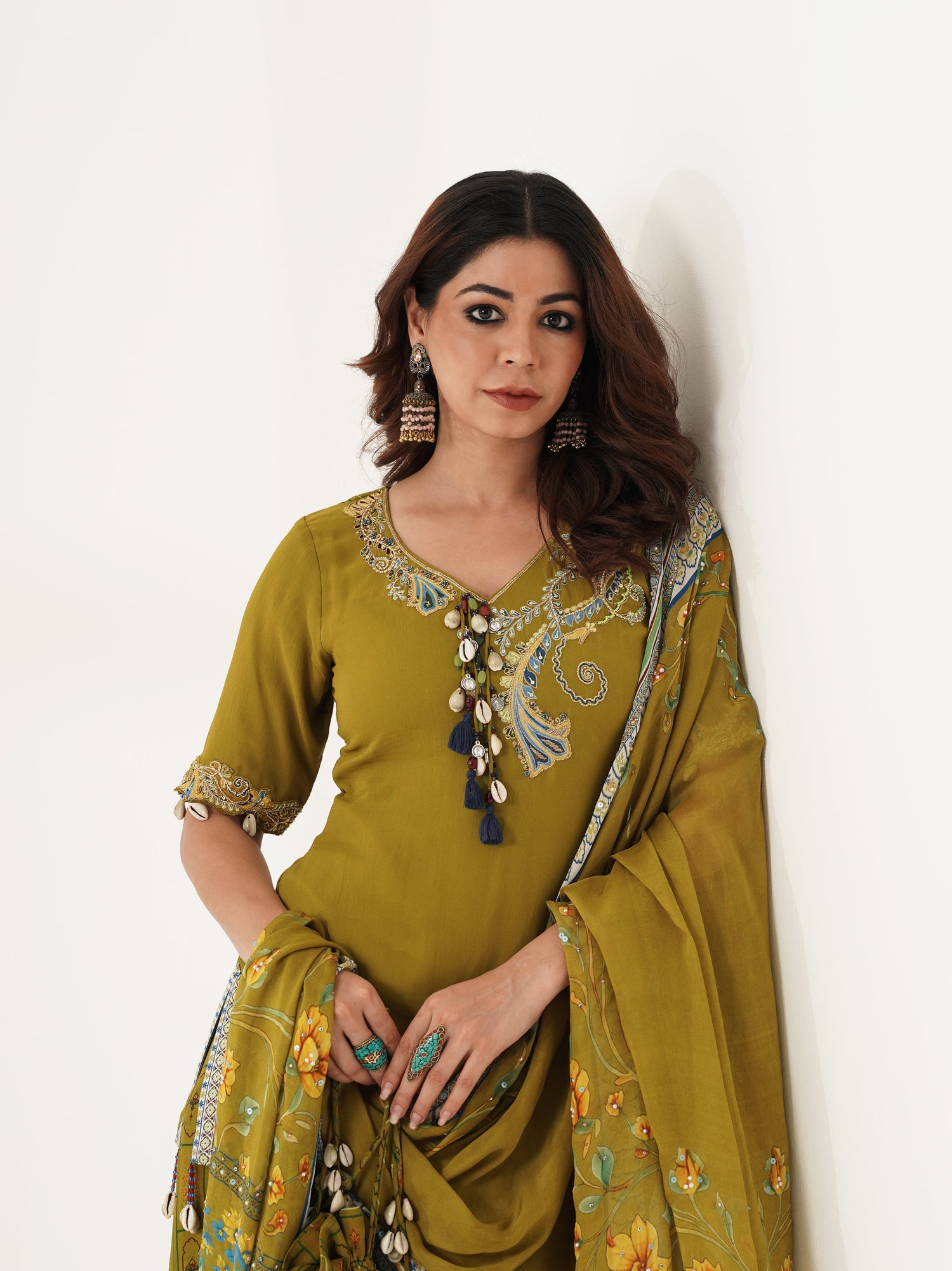 Woman wearing an olive green embroidered outfit with traditional jhumka earrings.