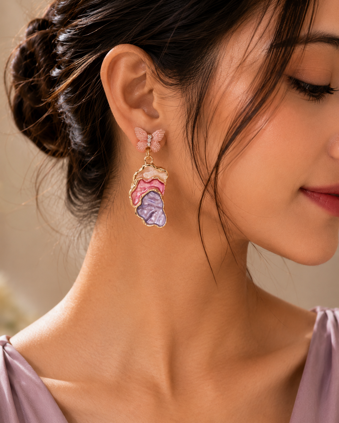 Blush butterfly pearl earrings styled on white fabric